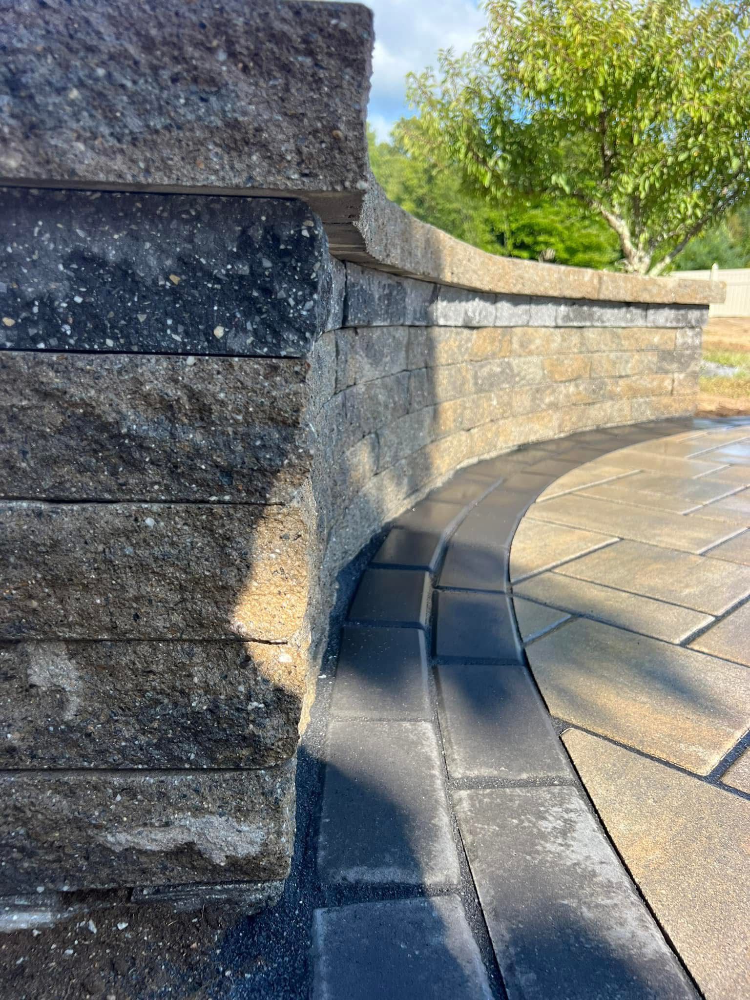 A close up of a brick wall with a curved patio in the background.