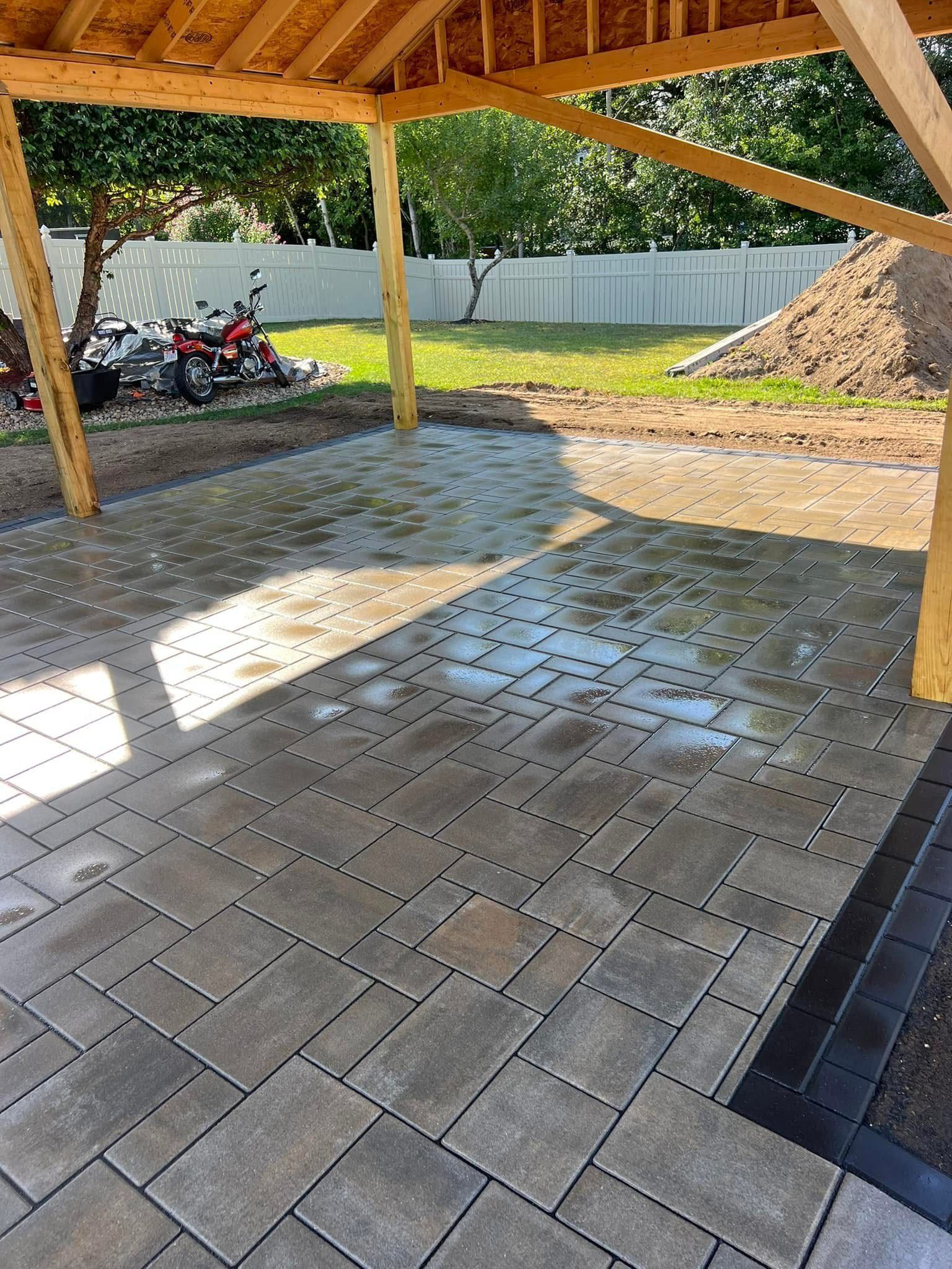 A patio with a wooden roof and a motorcycle parked underneath it.