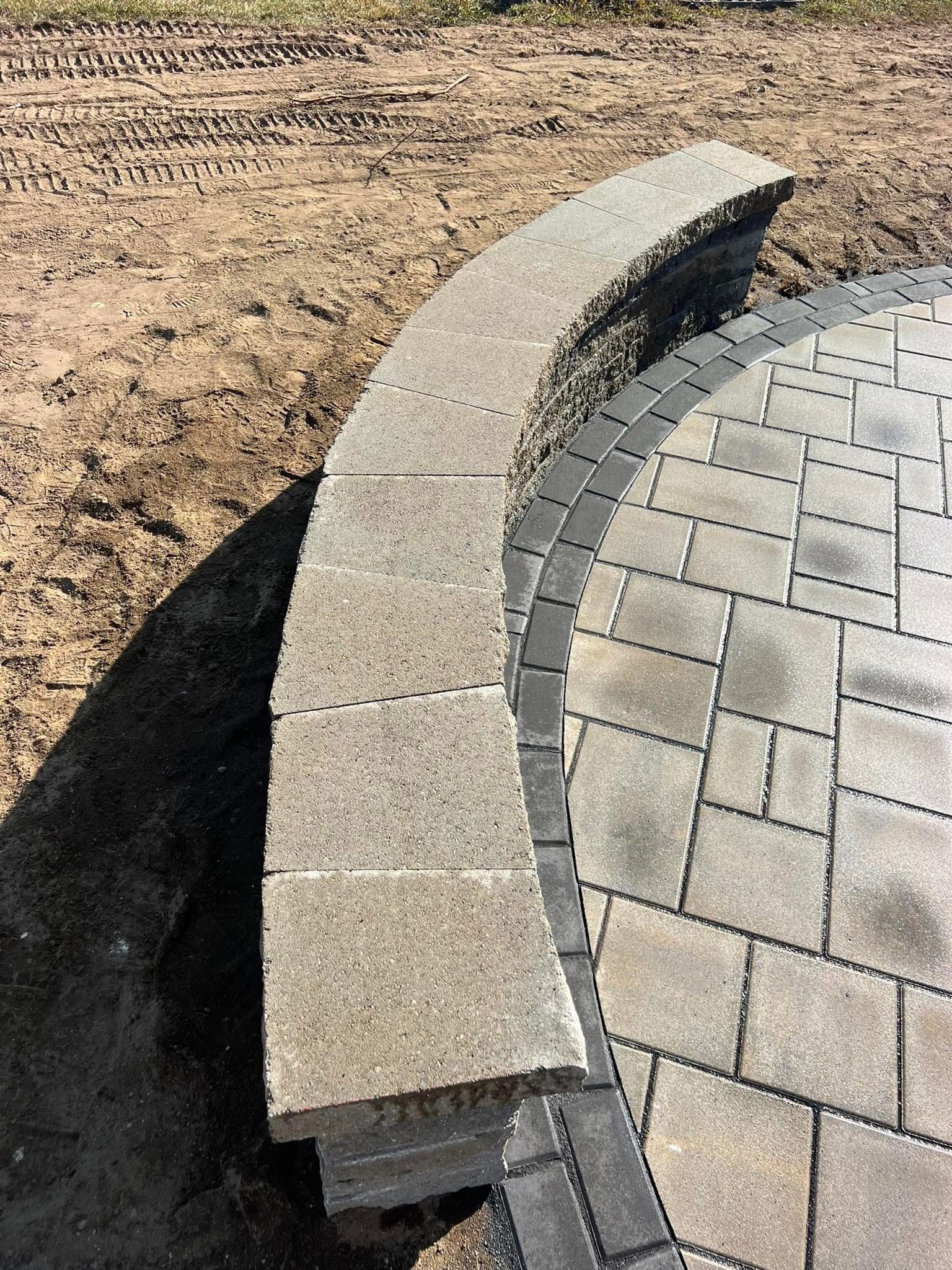 A brick wall is sitting on top of a brick patio.
