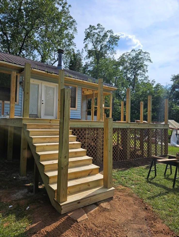 A house with a wooden deck and stairs in front of it.
