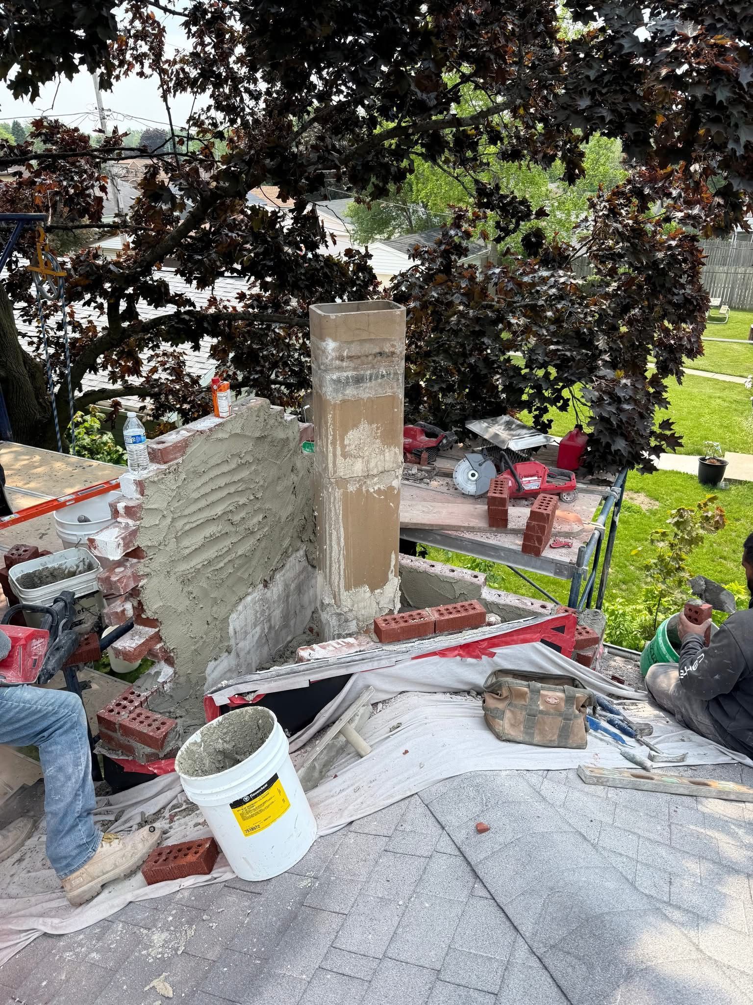 A bucket of cement is sitting on the ground next to a pile of bricks.