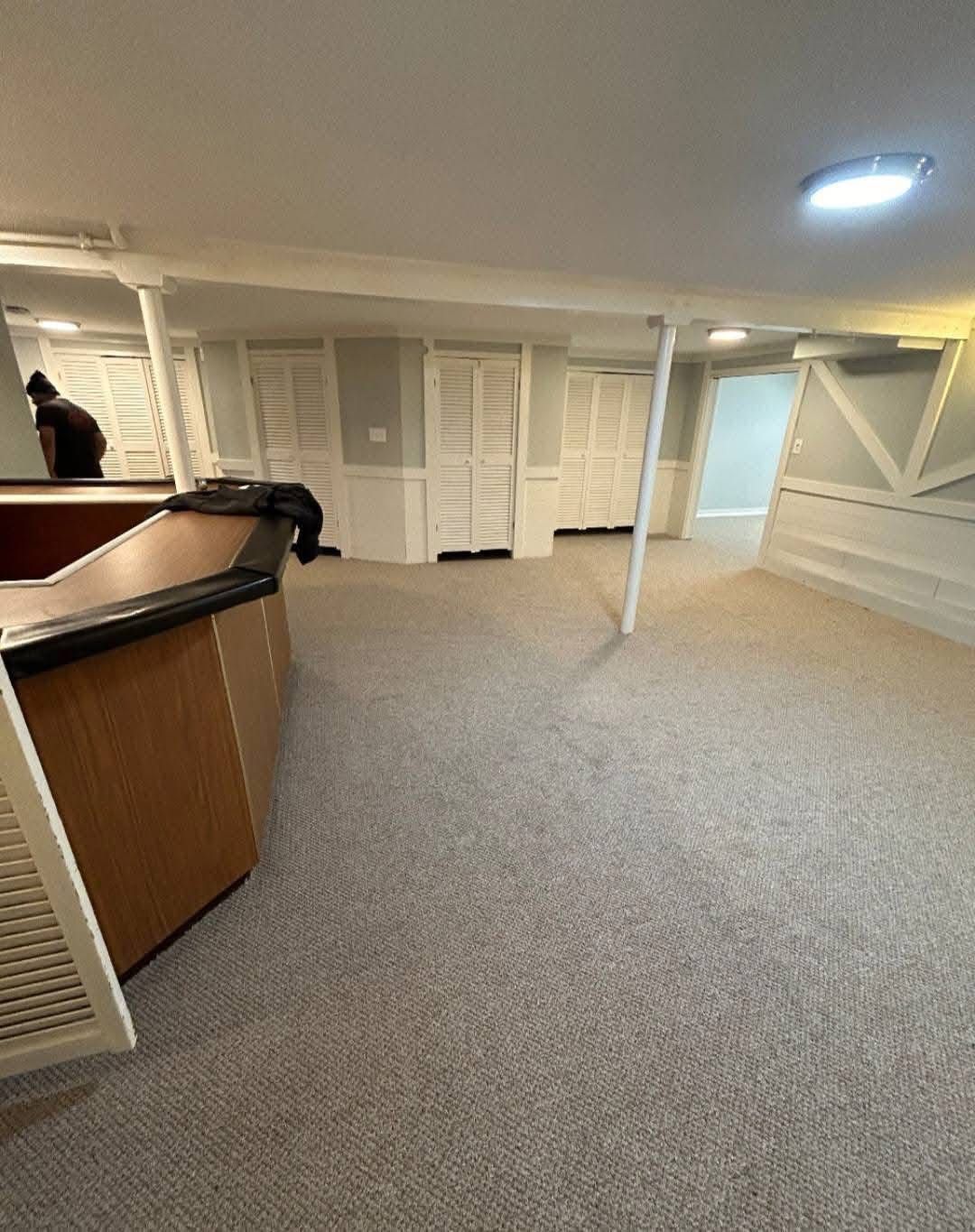 A large empty room with a carpeted floor and a counter.