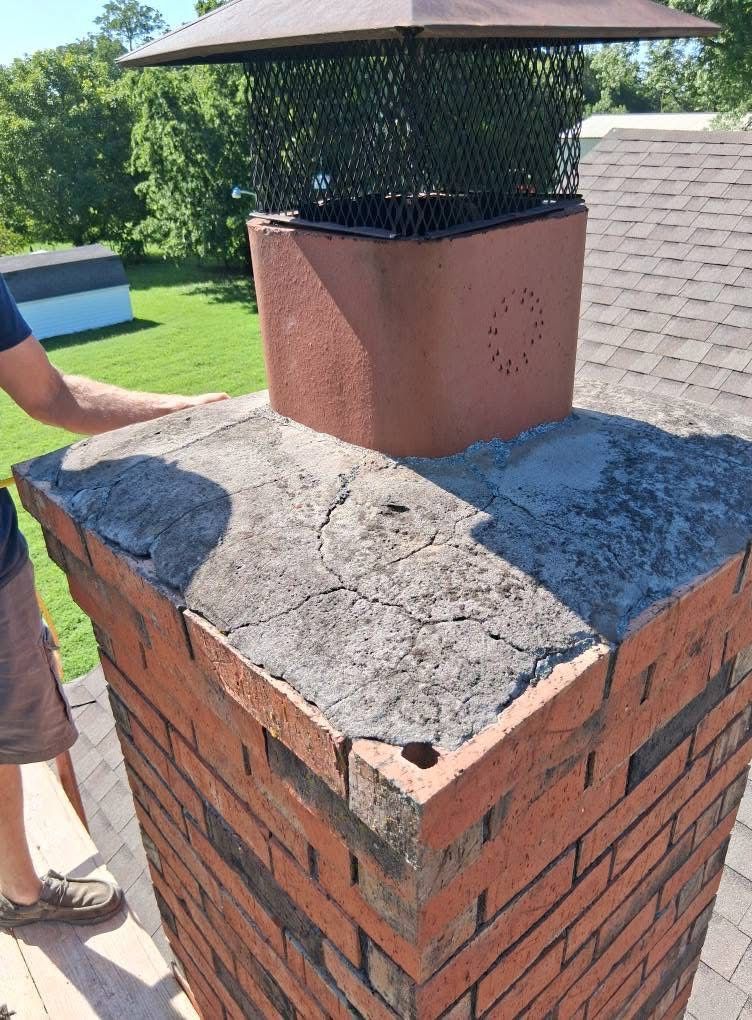 A man is standing next to a brick chimney on a roof.