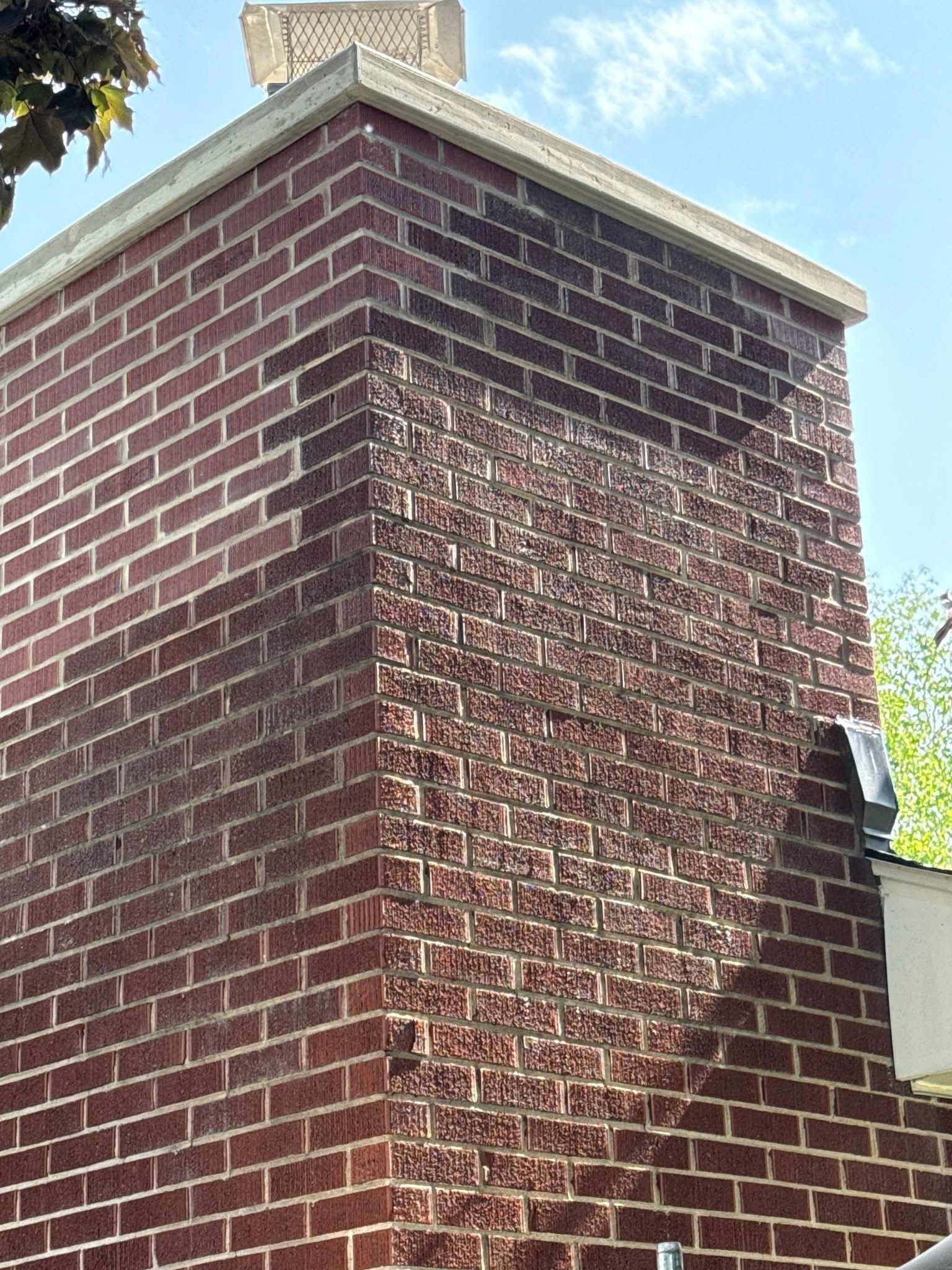 A close up of a brick chimney on the side of a house.