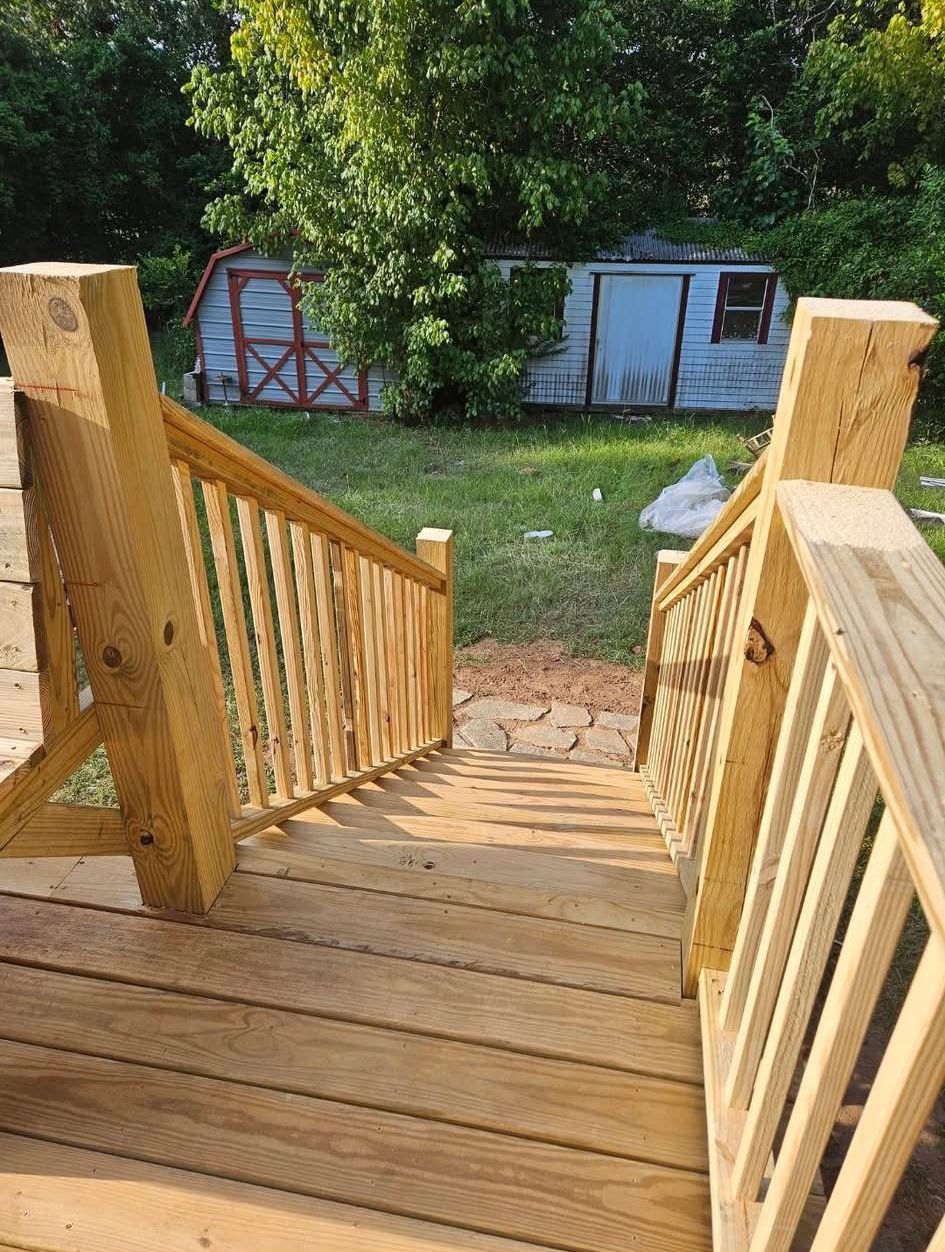 A wooden deck with stairs leading up to a backyard.