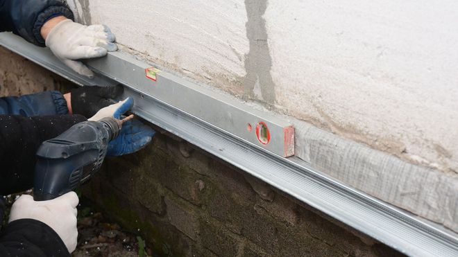 A man is using a level to level a brick wall.
