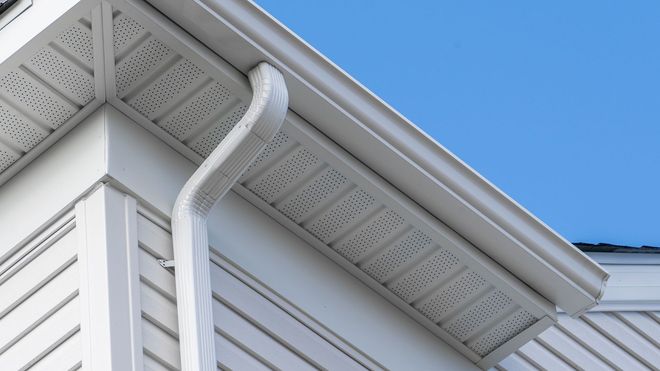 A white house with a gutter on the side of it