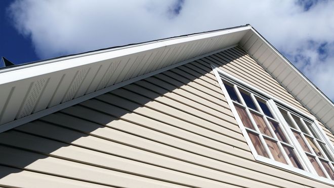 Looking up at the roof of a house with a blue sky in the background