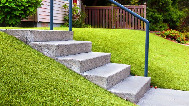 A set of stairs leading up to a house with a blue railing