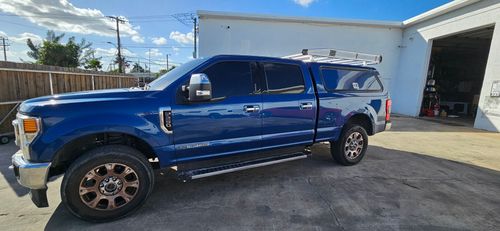 Blue pickup truck parked beside a white building on a sunny day
