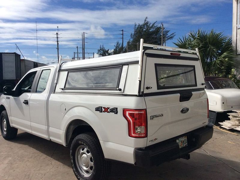 White 4x4 pickup truck with canopy parked outdoors under a blue sky