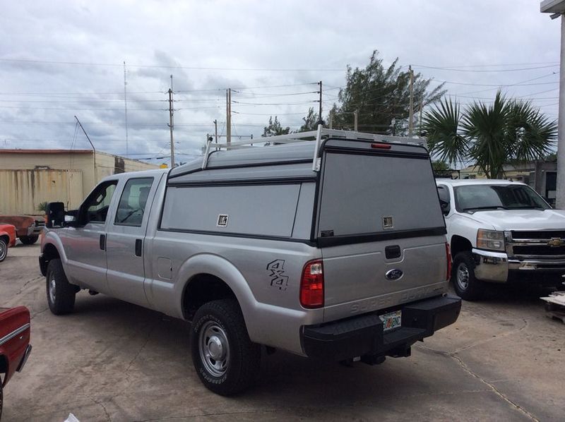 Silver pickup truck with canopy parked in a lot on a cloudy day