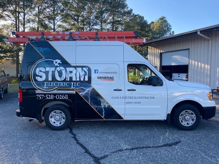 White utility van with &ldquo;STORM Electric&rdquo; logo parked beside a building, with a ladder on top