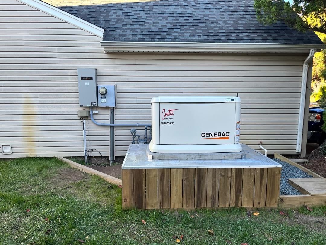 Residential backup generator on a concrete pad beside a house with utility meters and siding.