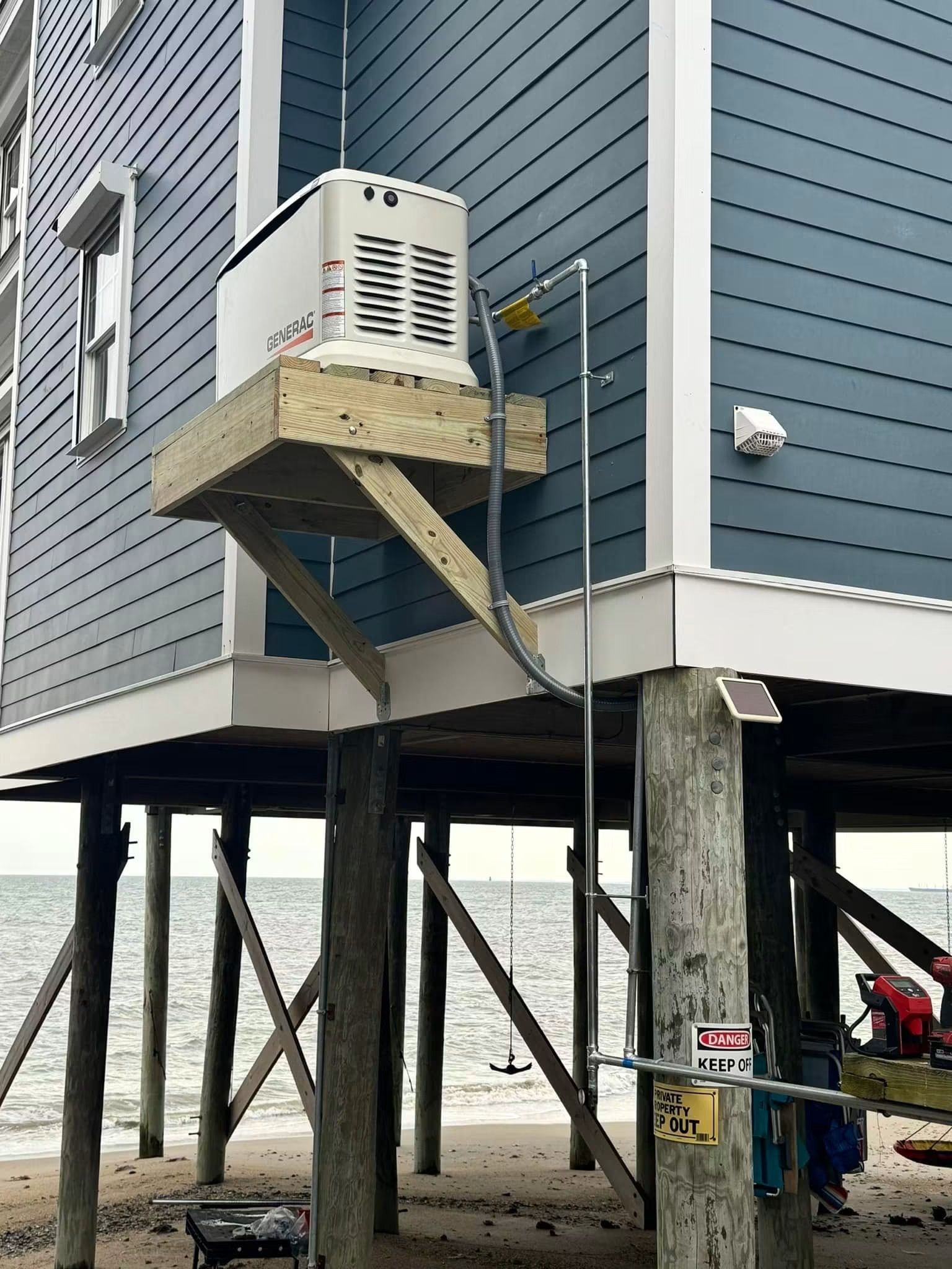 Exterior HVAC unit on a house mounted on a small platform above the ground on stilts