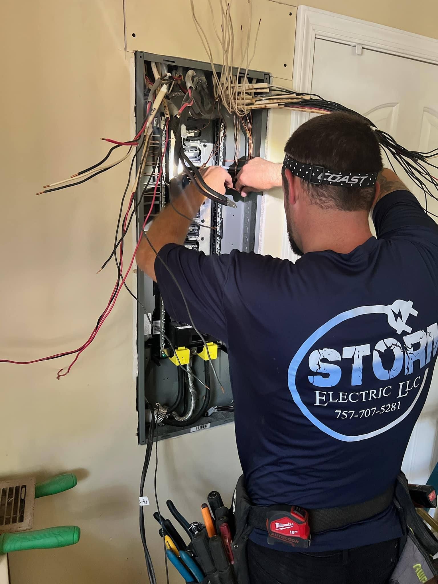 Electrician wiring an open wall panel with exposed cables in a home interior.