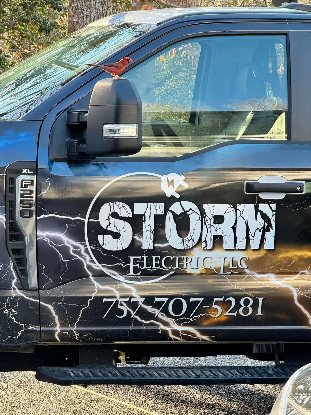 Black pickup truck with “STORM ELECTRIC” logo and phone number on the door