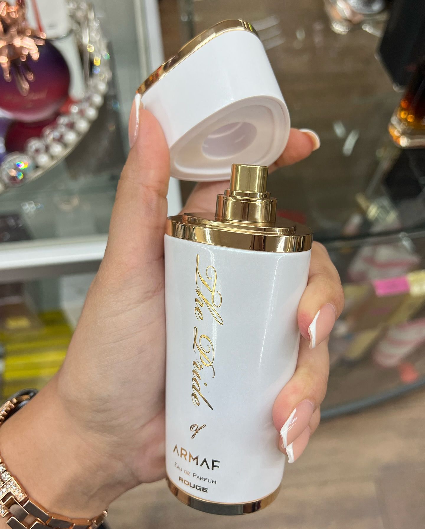 A woman is holding a bottle of armaf perfume