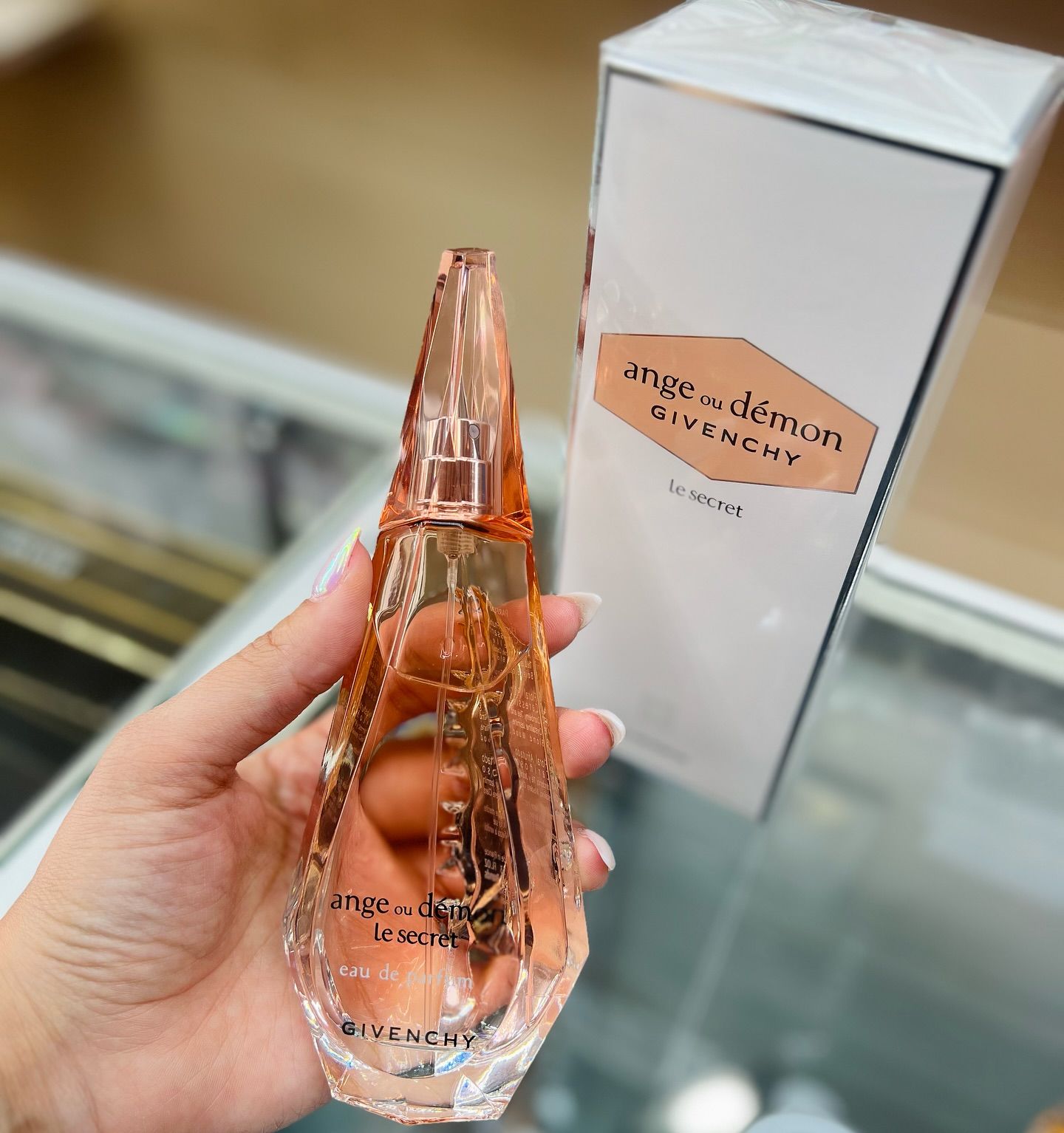 A person is holding a bottle of angel demon givenchy perfume