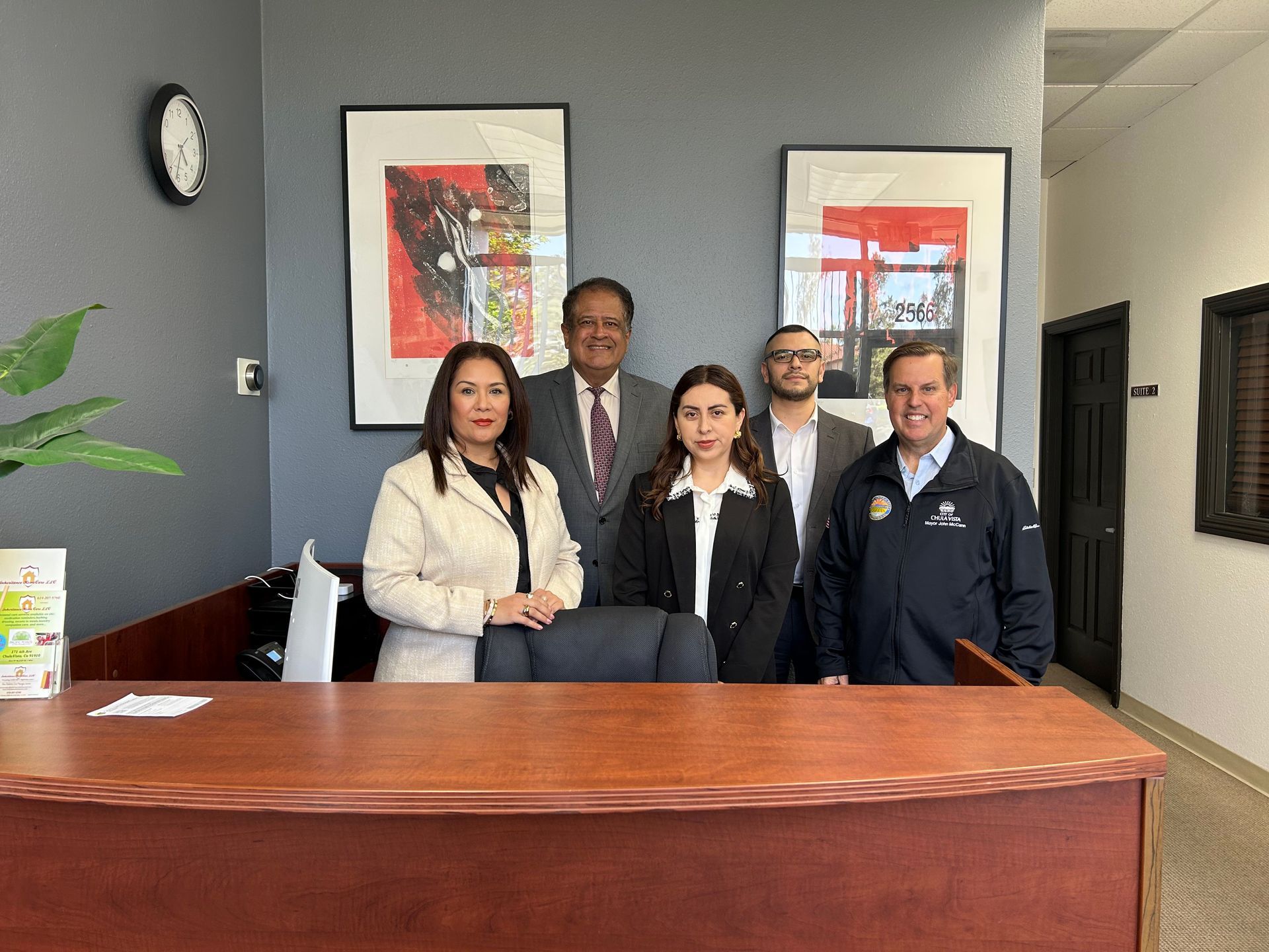 A group of people are posing for a picture in front of a desk in an office.
