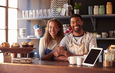 A man and a woman are standing behind a counter in a restaurant.