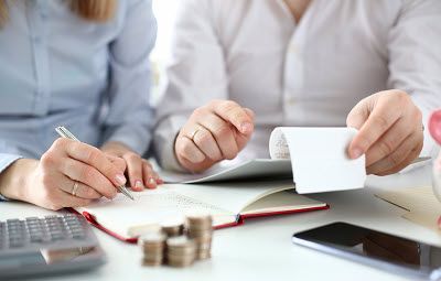 A man and a woman are sitting at a table looking at a receipt.