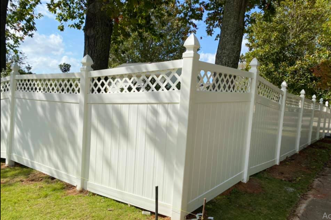 White vinyl privacy fence with lattice top, in a yard.