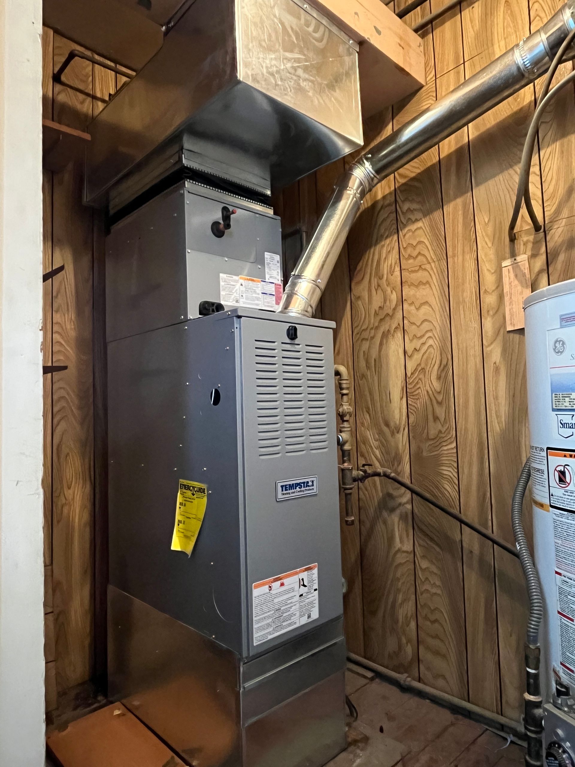 An air conditioner is sitting in a room next to a wooden wall.