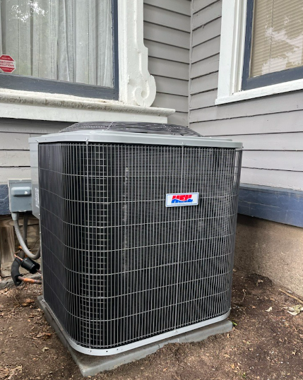 A large air conditioner is sitting on the side of a house.