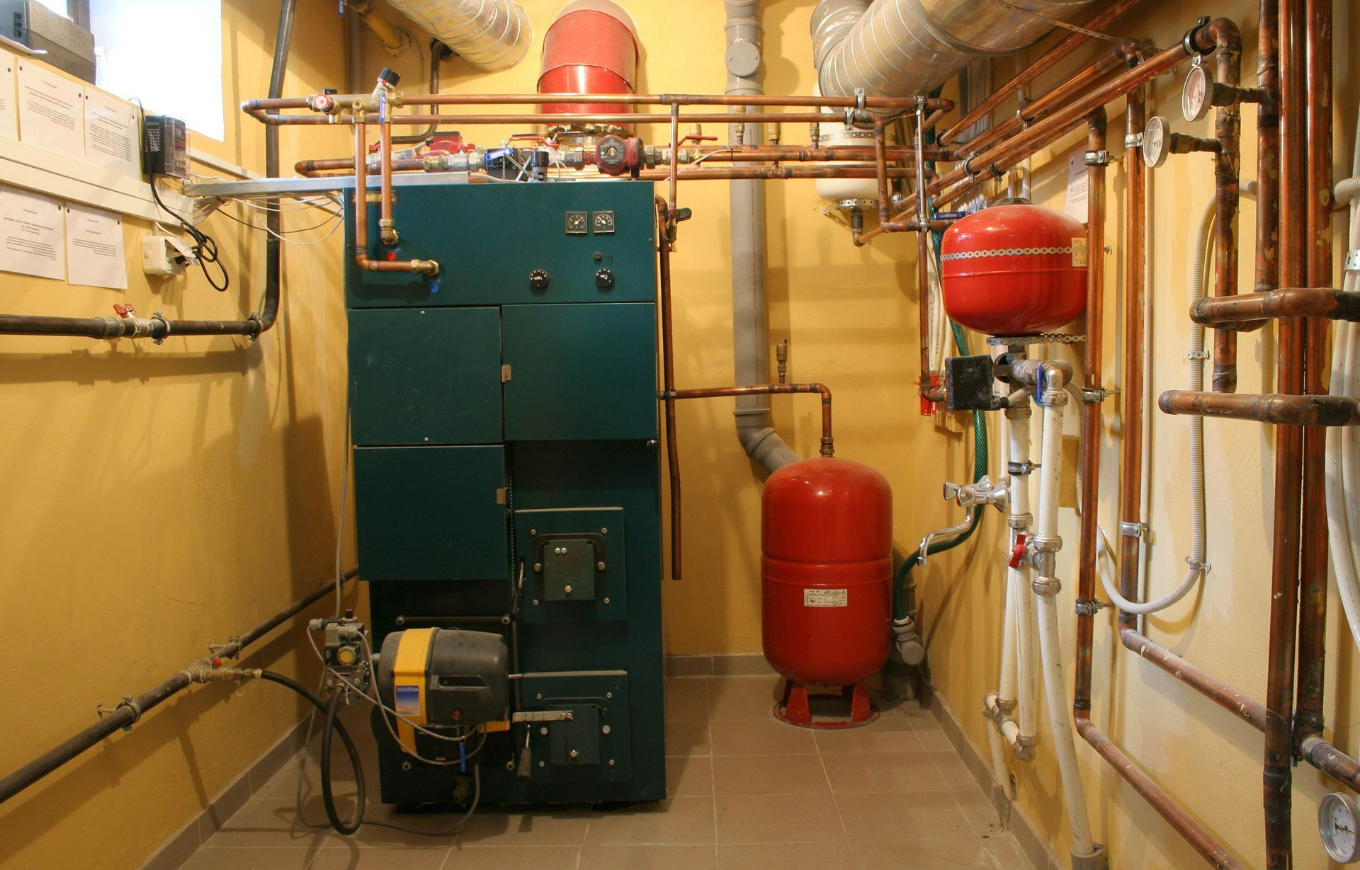 A room with a green boiler and a red tank