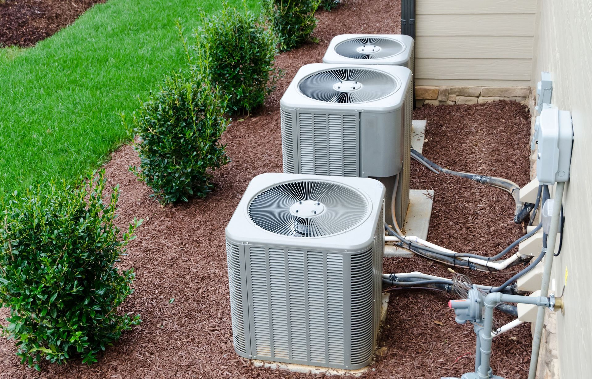 A row of air conditioners are sitting on the side of a building.