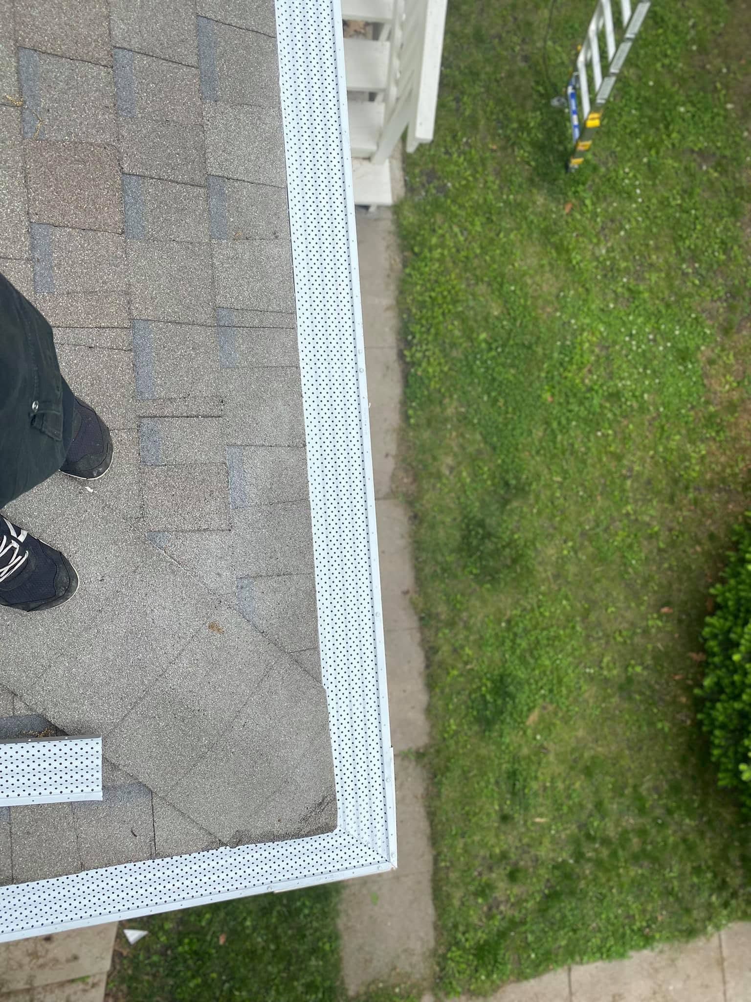 Overhead view of a sidewalk with a white border, grass, and part of a person's shoe at the edge