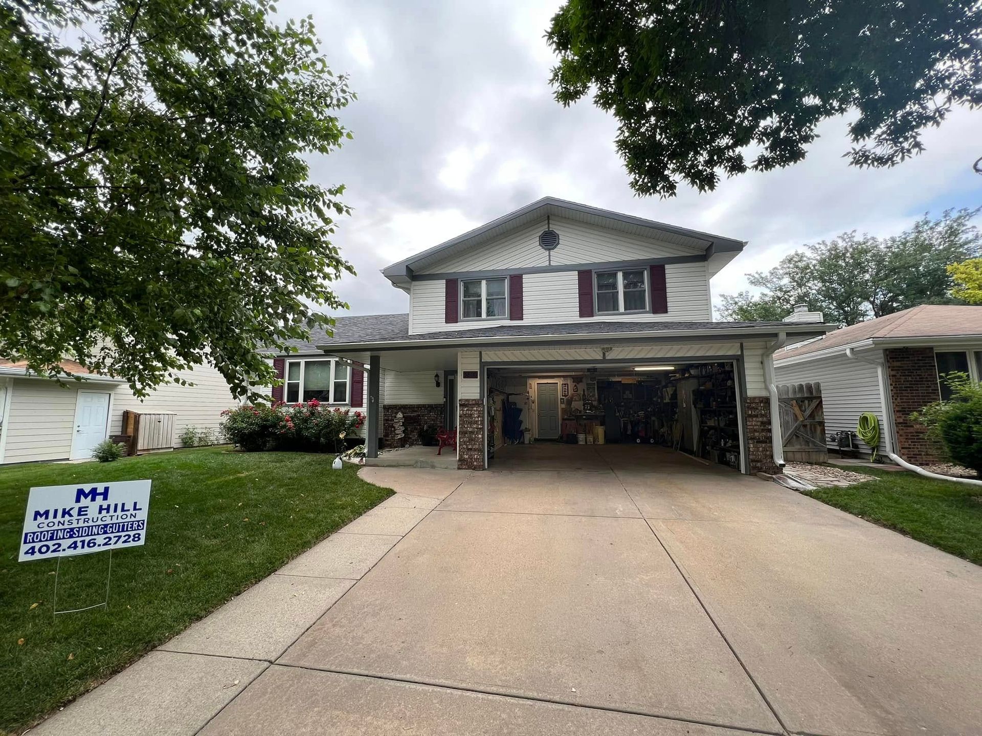Two-story suburban house with a wide driveway and a yard sign reading 