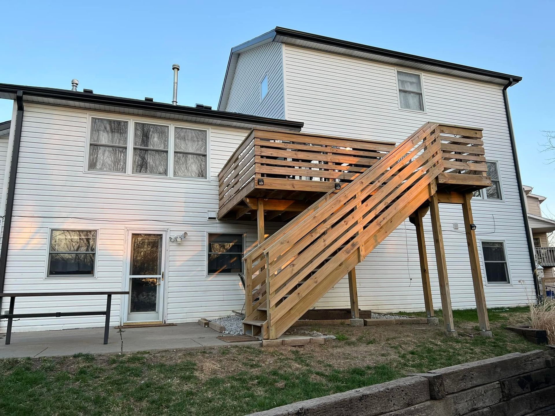 Two-story white house with a large wooden exterior staircase leading to the upper level.