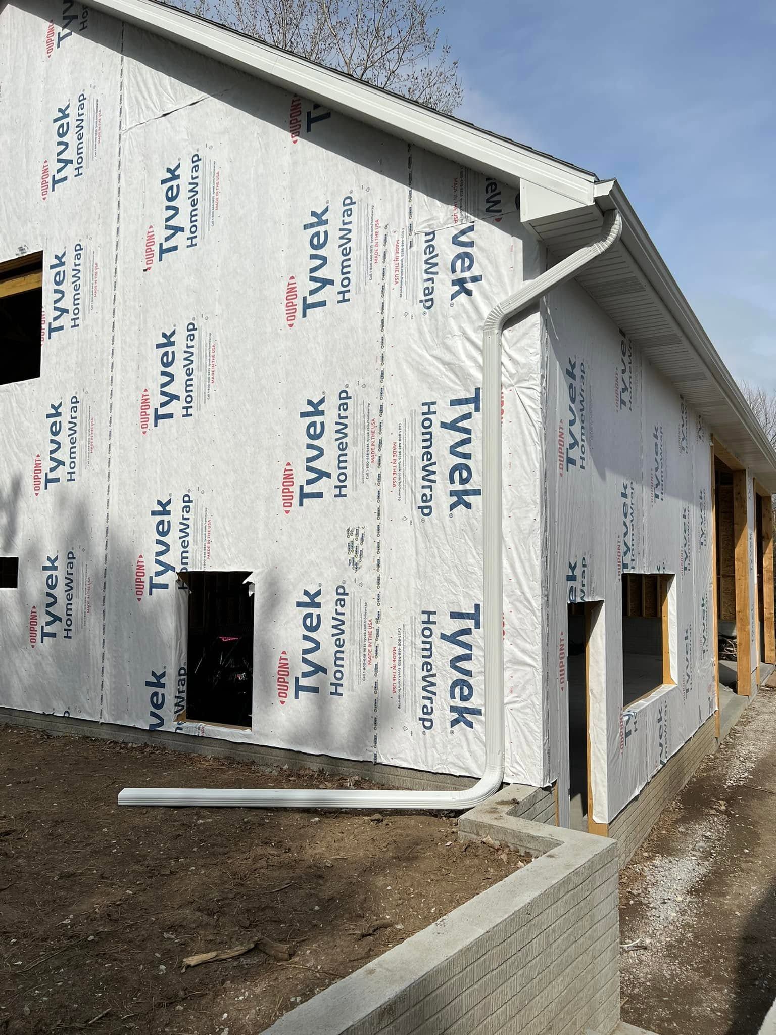 Construction site with house wrapped in Tyvek house wrap and unfinished exterior walls.