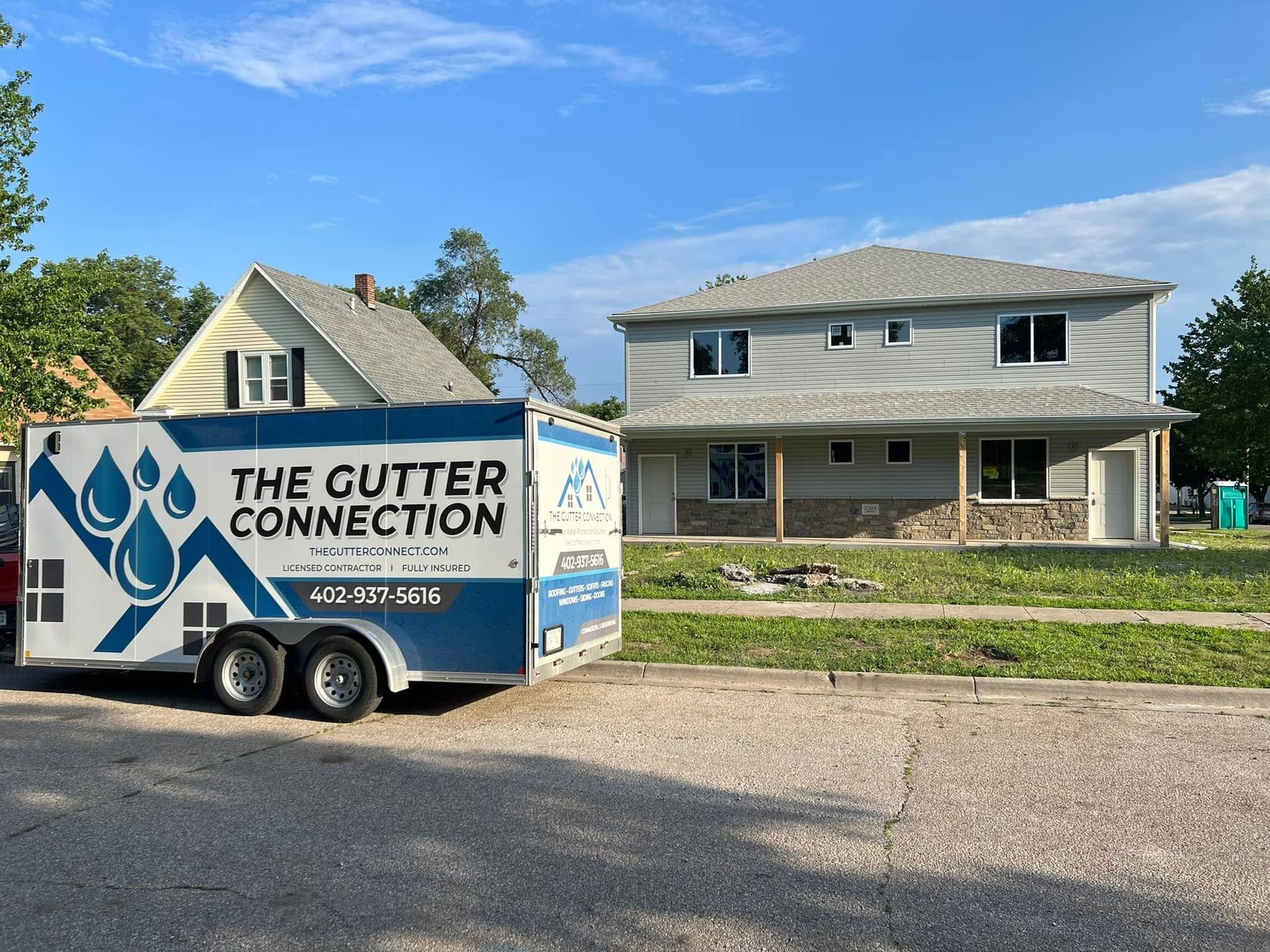 The Clutter Connection moving truck parked in front of a two-story house on a sunny day