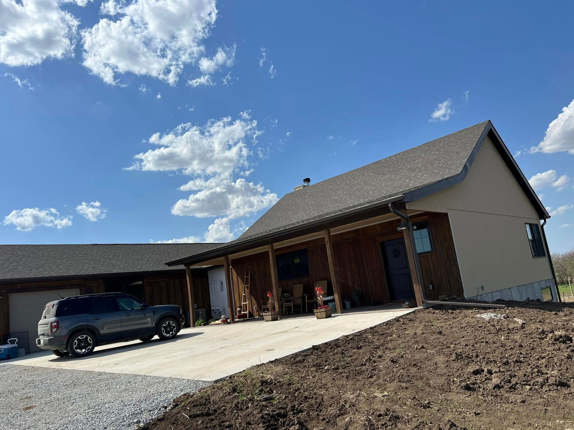 New suburban house with a black SUV parked in the driveway under a blue sky