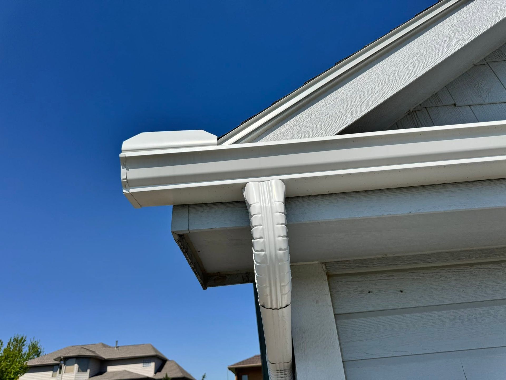 White house roof and gutter against a clear blue sky
