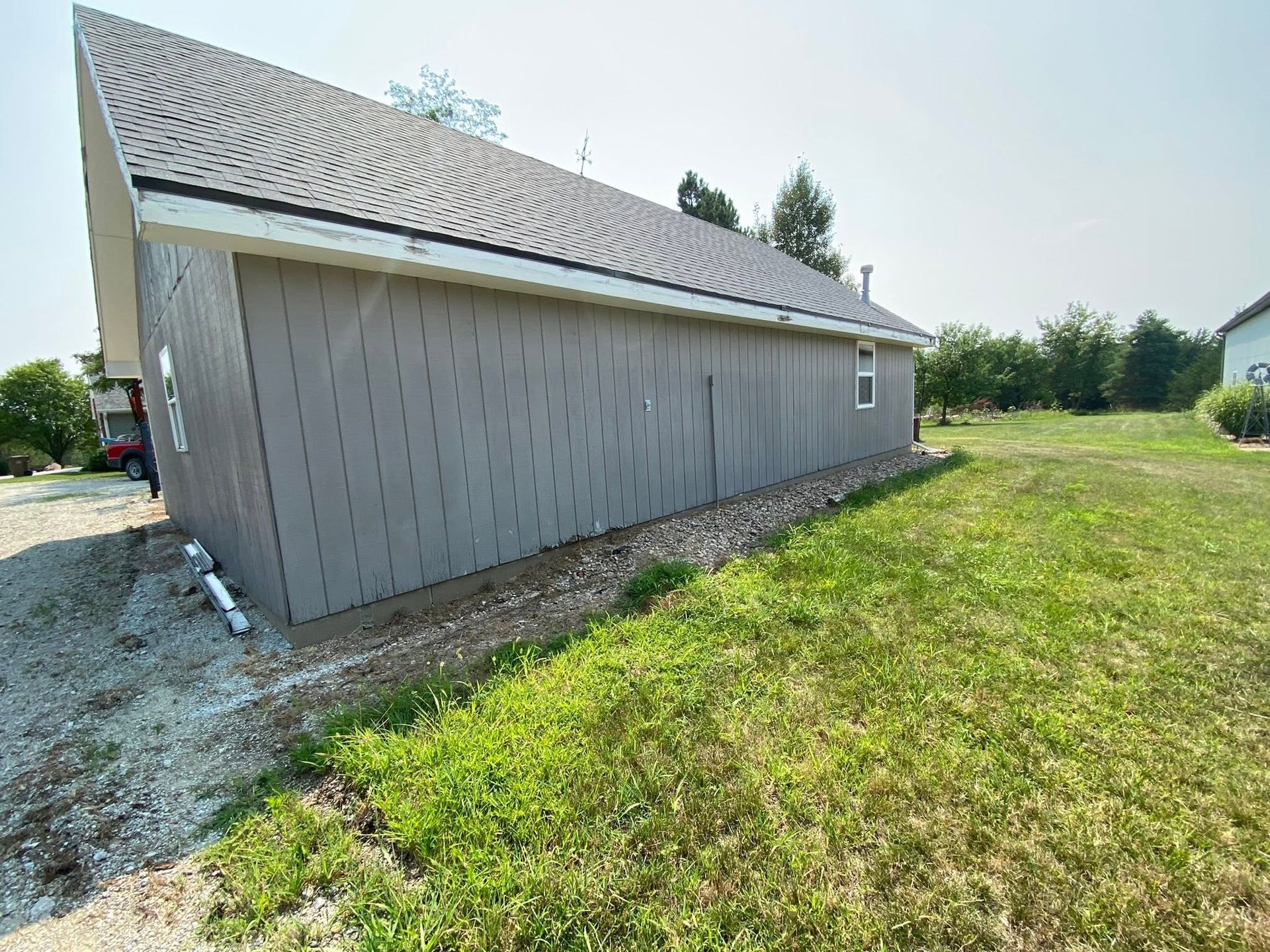 Gray-sided barn or shed beside a grassy field under a bright sky