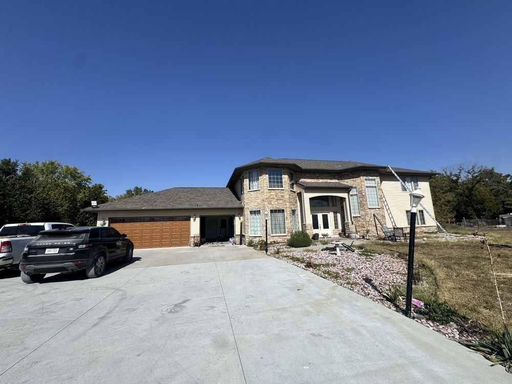 Stone house with a driveway, black truck, and clear blue sky