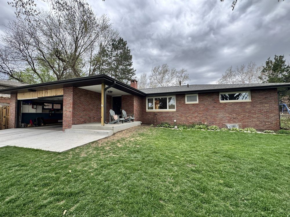 Brick ranch house with attached carport, concrete driveway, and cloudy sky
