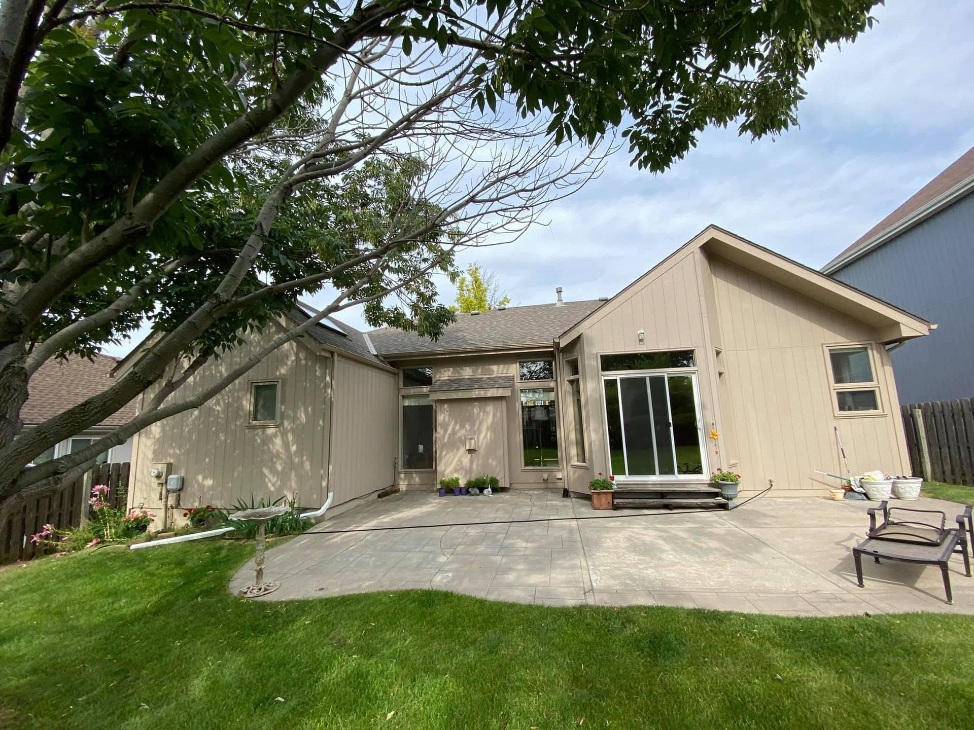 Suburban house with a patio, green lawn, and trees in the yard