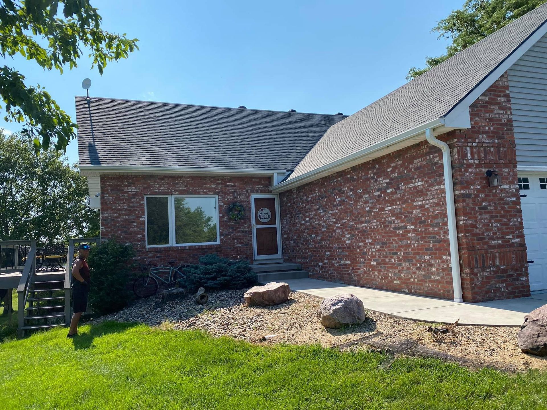 Brick house exterior with red brick walls, white trim, and a small rock garden in front.