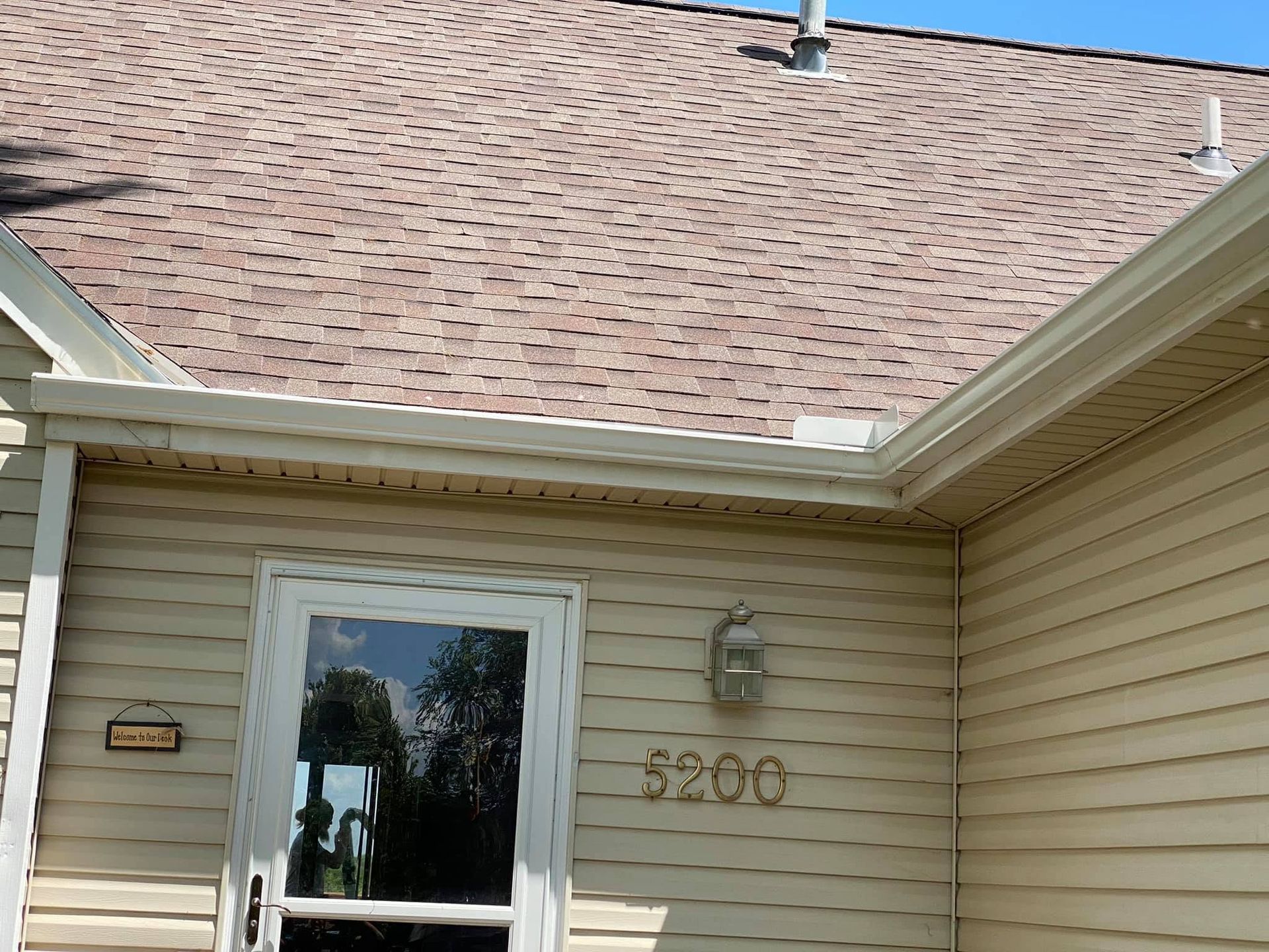 House exterior with beige siding, large shingled roof, front door, and number 5200 displayed near the entrance