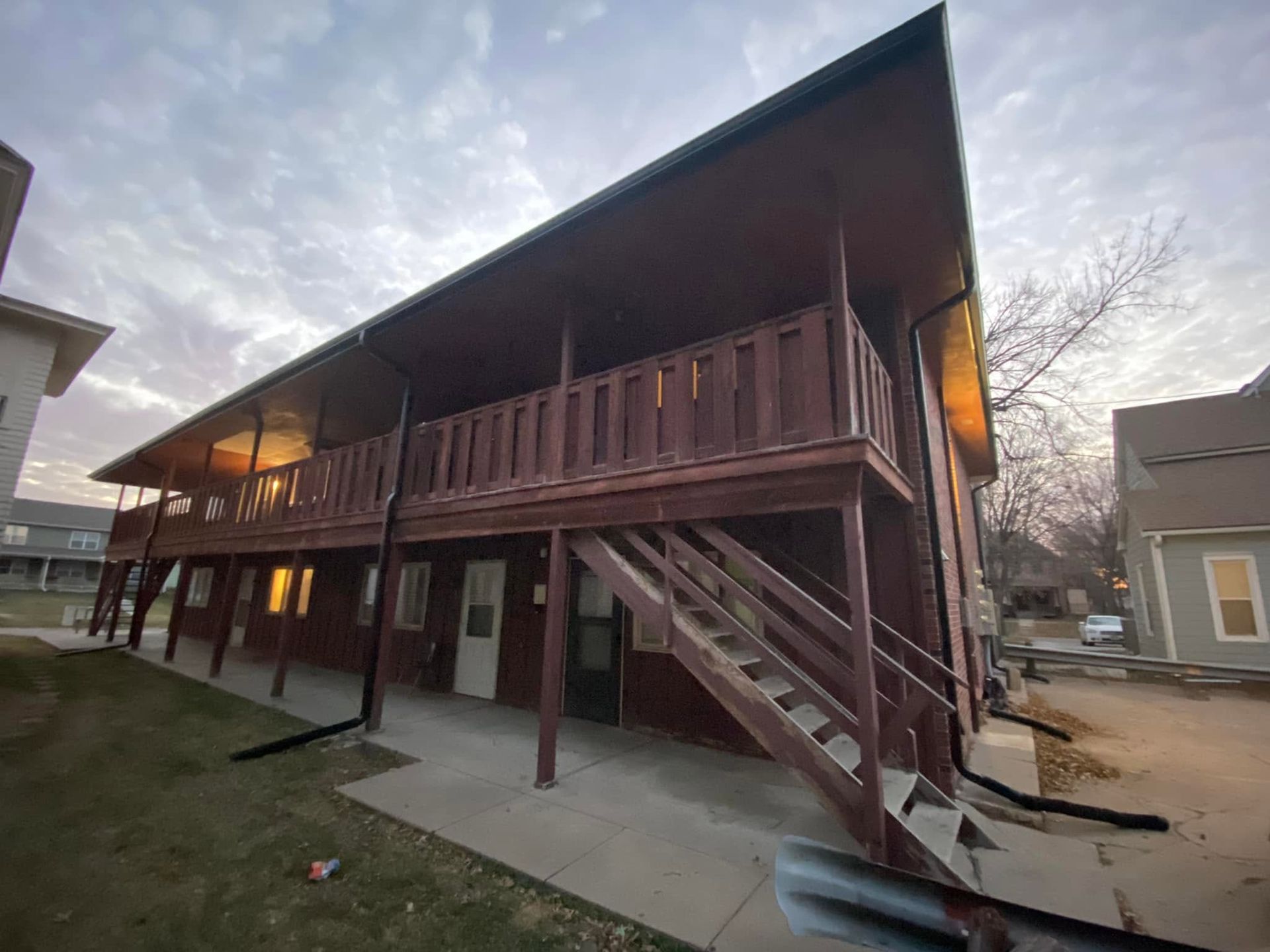Two-story wooden building with exterior stairs and porch at dusk