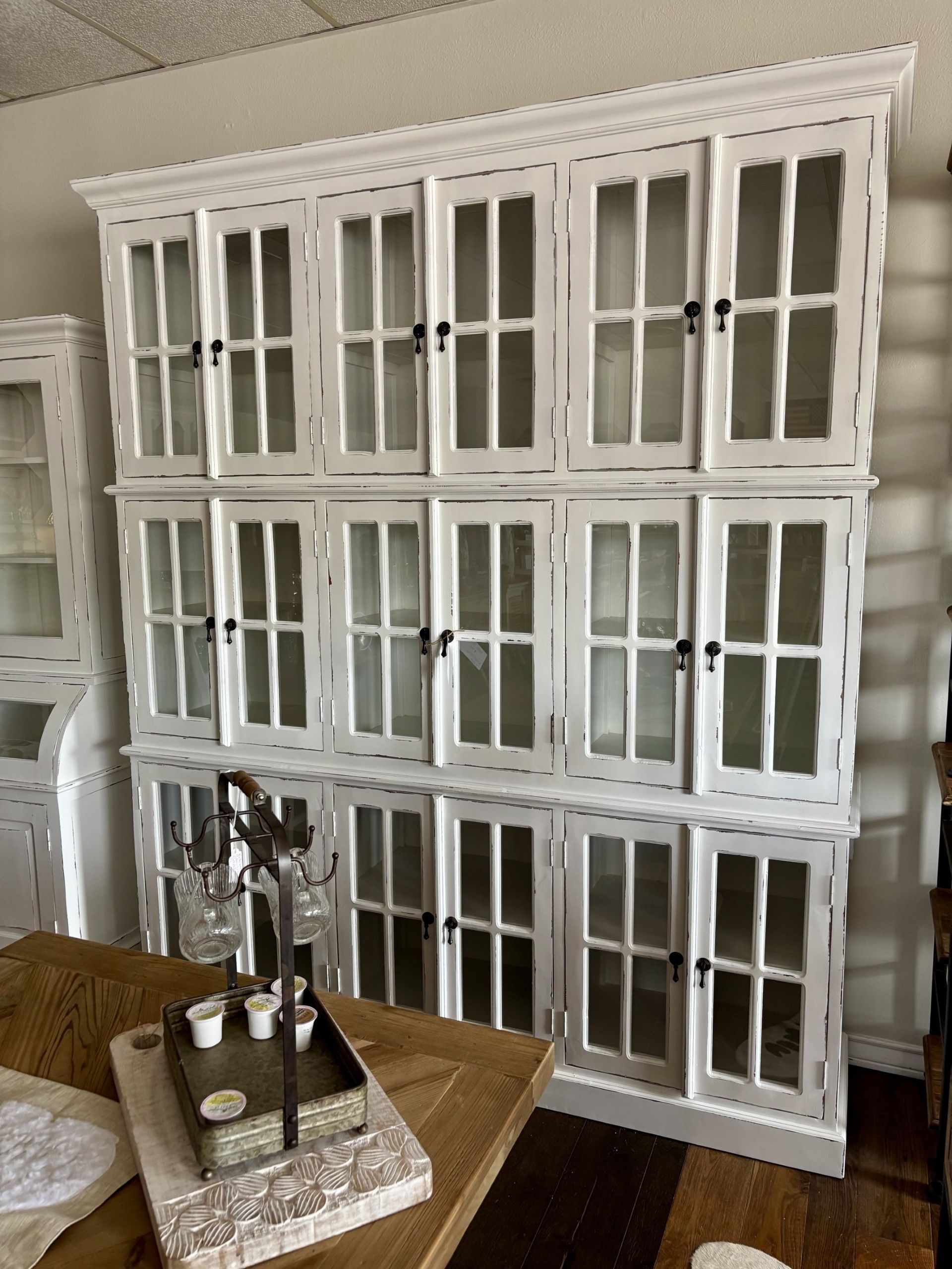 A large white cabinet with glass doors is in a living room.