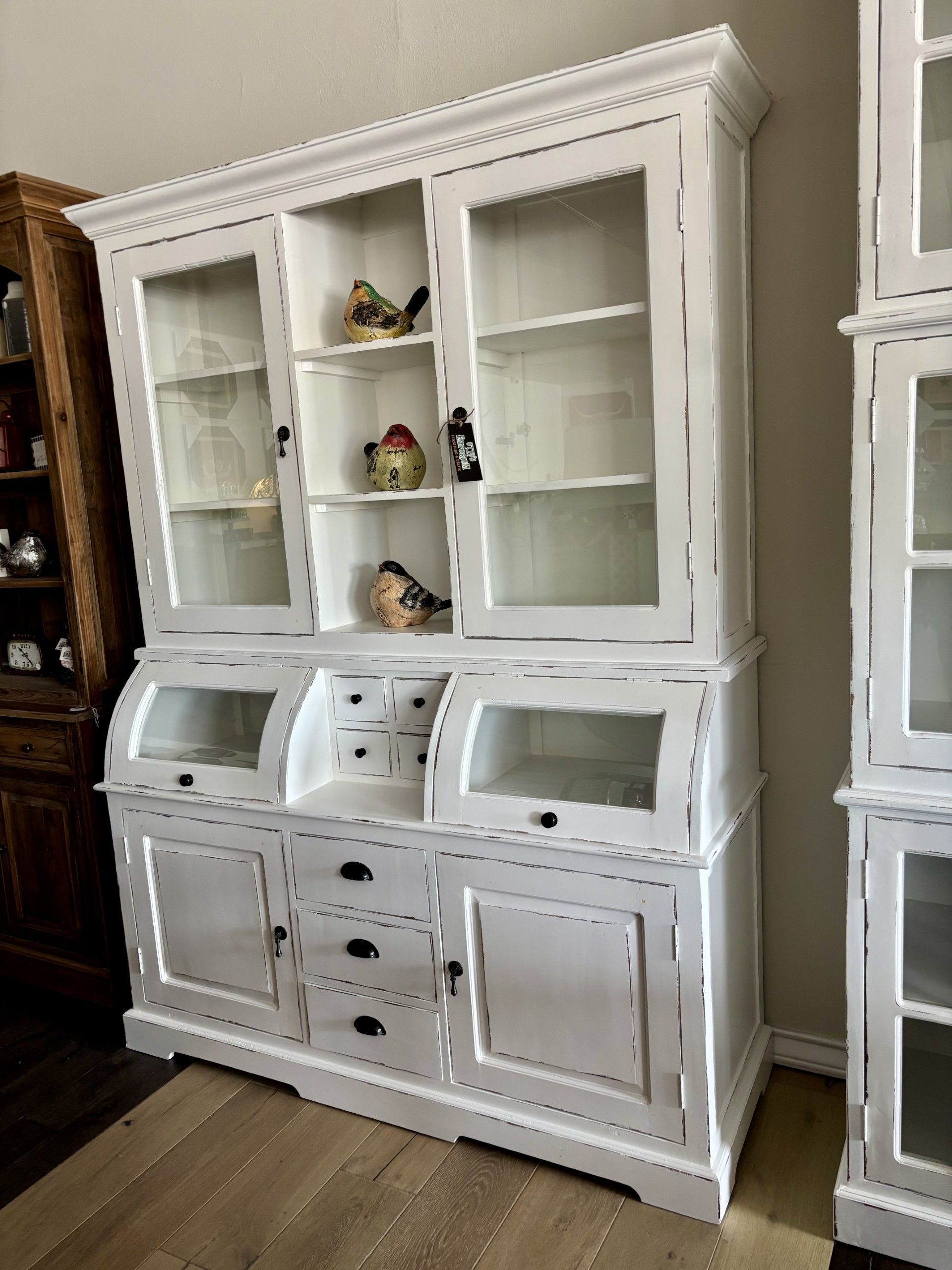 A white cabinet with glass doors and drawers in a room.