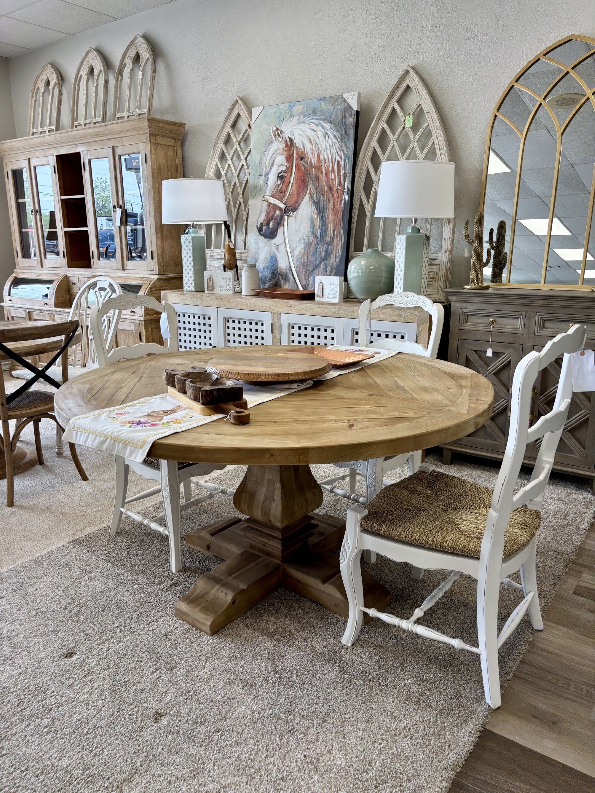 A dining room with a table and chairs and a painting of a horse on the wall.