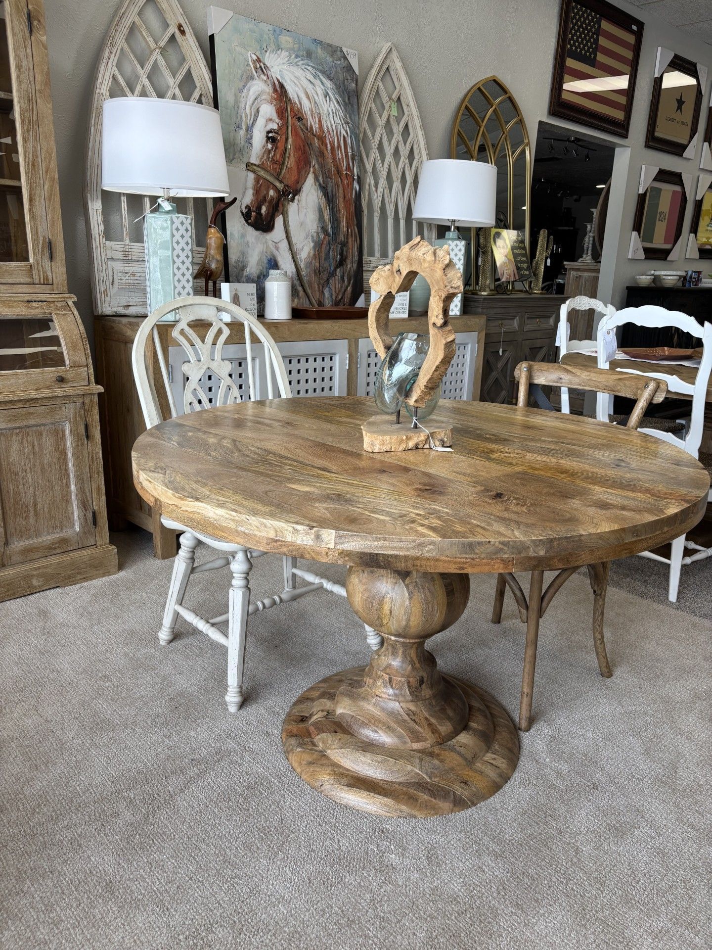A wooden table and chairs in a room with a painting of a horse on the wall.