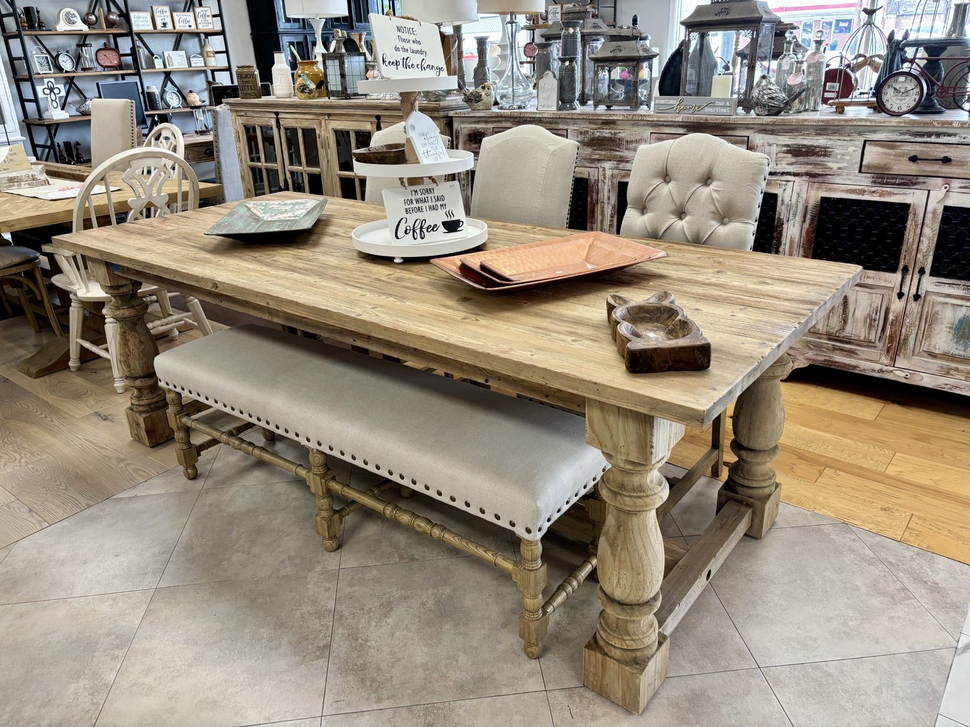 A wooden dining table with a bench and chairs in a store.